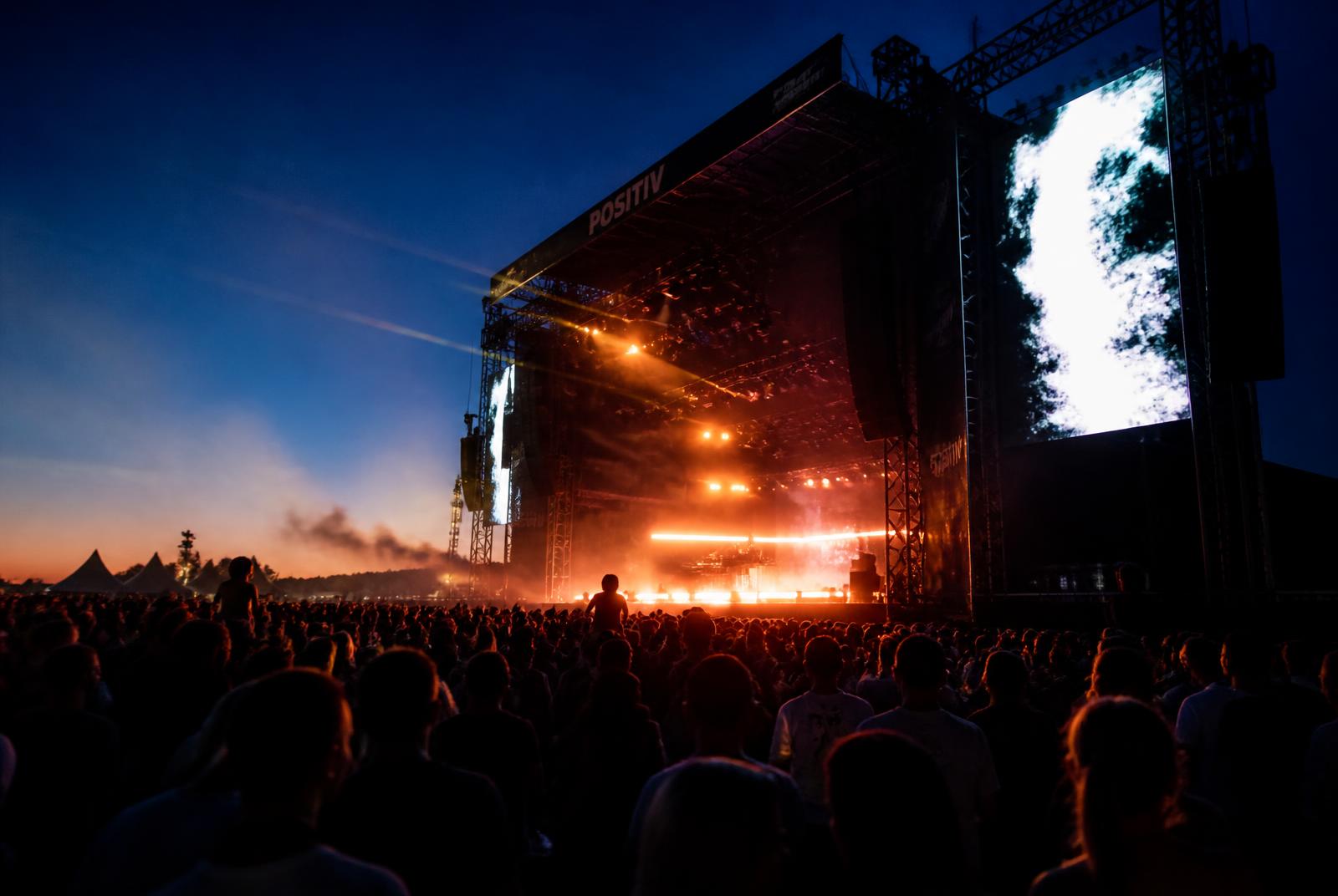 Festival main stage with LED screens and crowd at blue hour